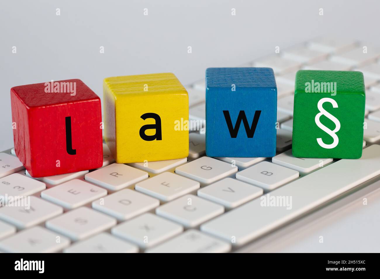 Farbige Spielzeugblöcke mit dem Wort Gesetz und einem Absatzzeichen stehen auf einer weißen Computertastatur Stockfoto