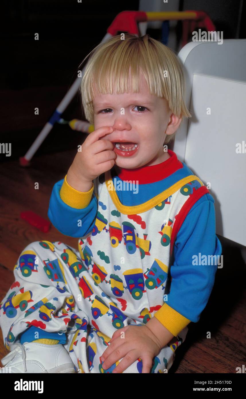 Ein unglücklich weinendes Kleinkind lässt alles auf dem Spielzimmerboden raus. Stockfoto