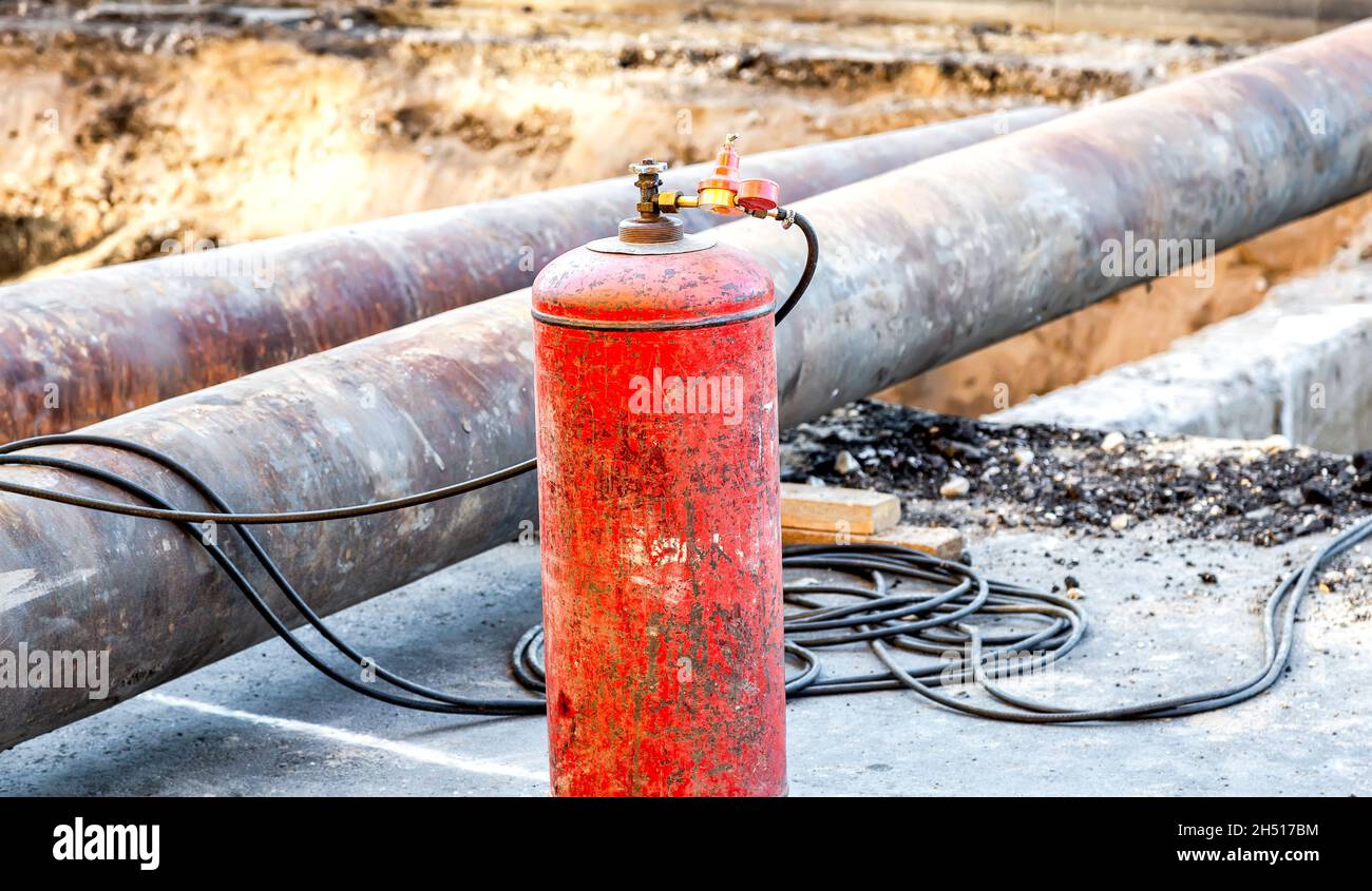 Rote Acetylenflasche mit Drucksensoren. Ausrüstung für das Schneiden von Metall mit Gas. Gasschweißanlage zum Schneiden von Metall auf einer Baustelle Stockfoto