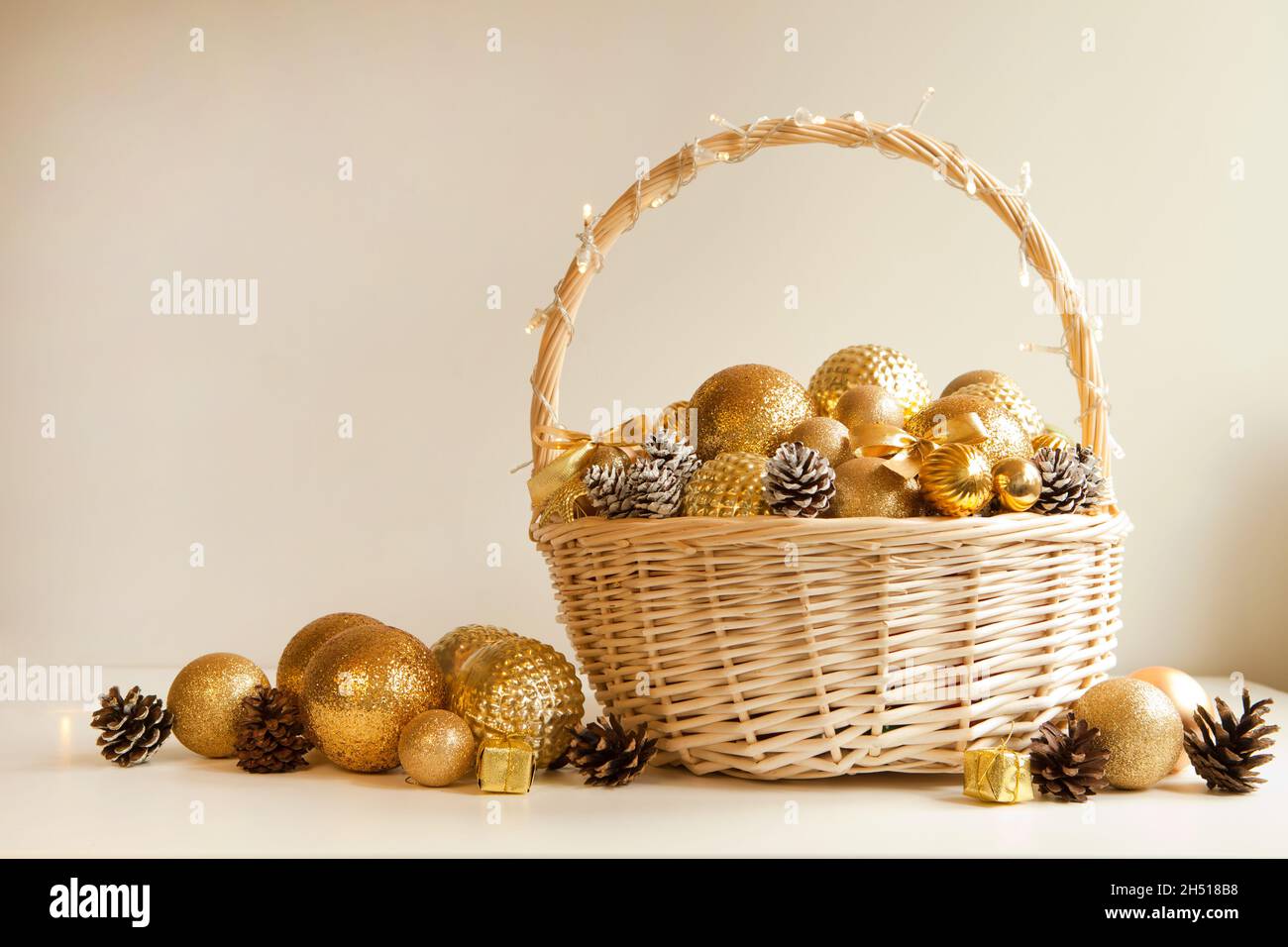 Riesiger Korbkorb, gefüllt bis an die Spitze mit goldenen Kugeln und Tannenzapfen, um Weihnachtstanne zu schmücken Stockfoto