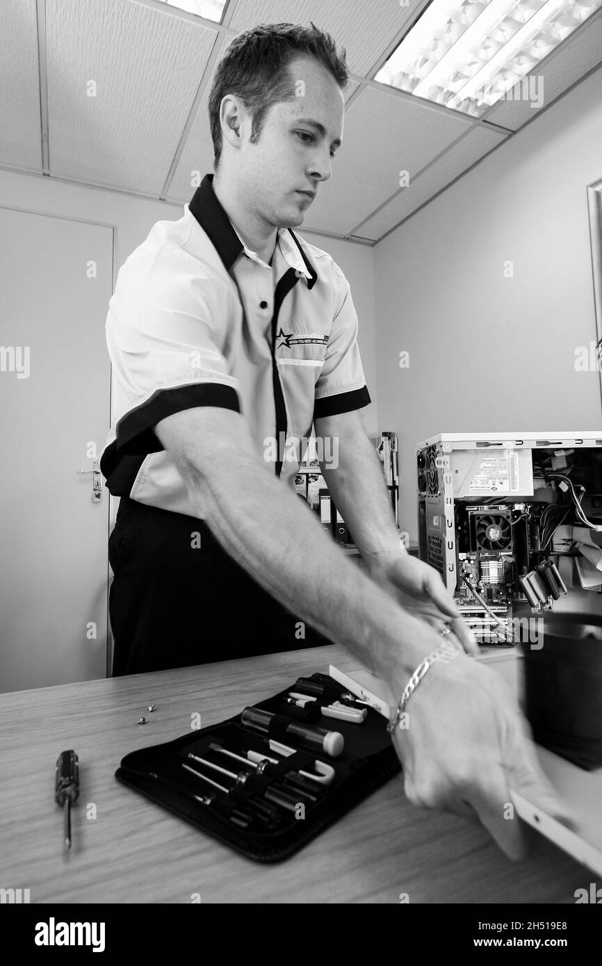 JOHANNESBURG, SÜDAFRIKA - 09. Aug 2021: Eine vertikale Graustufe eines IT-Service- und Wartungsexperten, der an einem Desktop-Computer in Johanes arbeitet Stockfoto