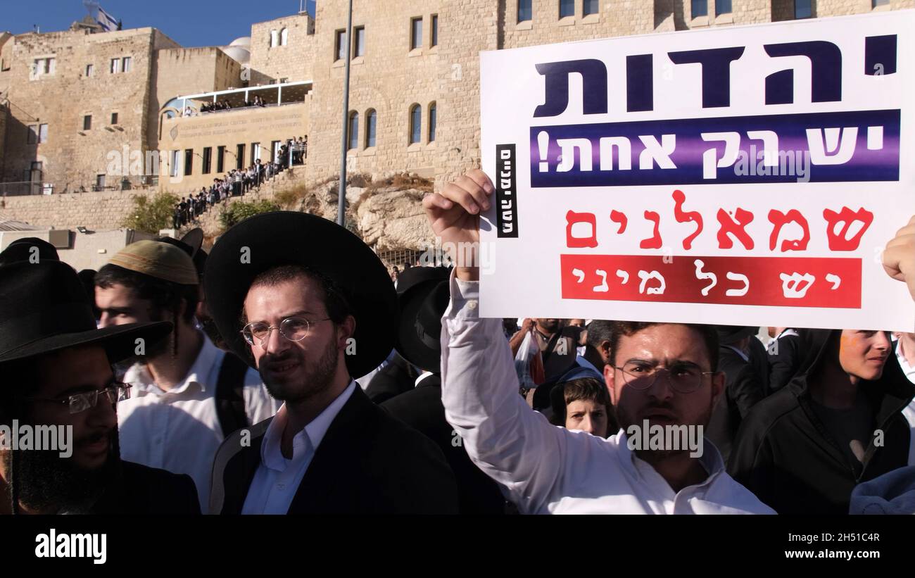 Ein Haredi-Jude hält ein Schild mit der Aufschrift „Judentum ist nur einer, Linke sind viele“, während sich Ultra-orthodoxe Juden während eines Protestes gegen „Frauen der Mauer“ versammeln. Beim Betreten des platzes der Westmauer mit Tora-Rollen in einer langjährigen Kampagne für die Gleichstellung der Geschlechter an dem Ort, der dem jüdischen Volk am 05. November 2021 in Jerusalem, Israel, geweiht ist. The Women of the Wall ist eine feministische Gebetsgruppe, die eine monatliche Gebetsstunde an der Western Wall veranstaltet und immer wieder behauptet hat, dass es keinen einzigen „Brauch des Ortes“ gibt und dass ihr Recht zu beten eine im ISR verankerte Religionsfreiheit ist Stockfoto