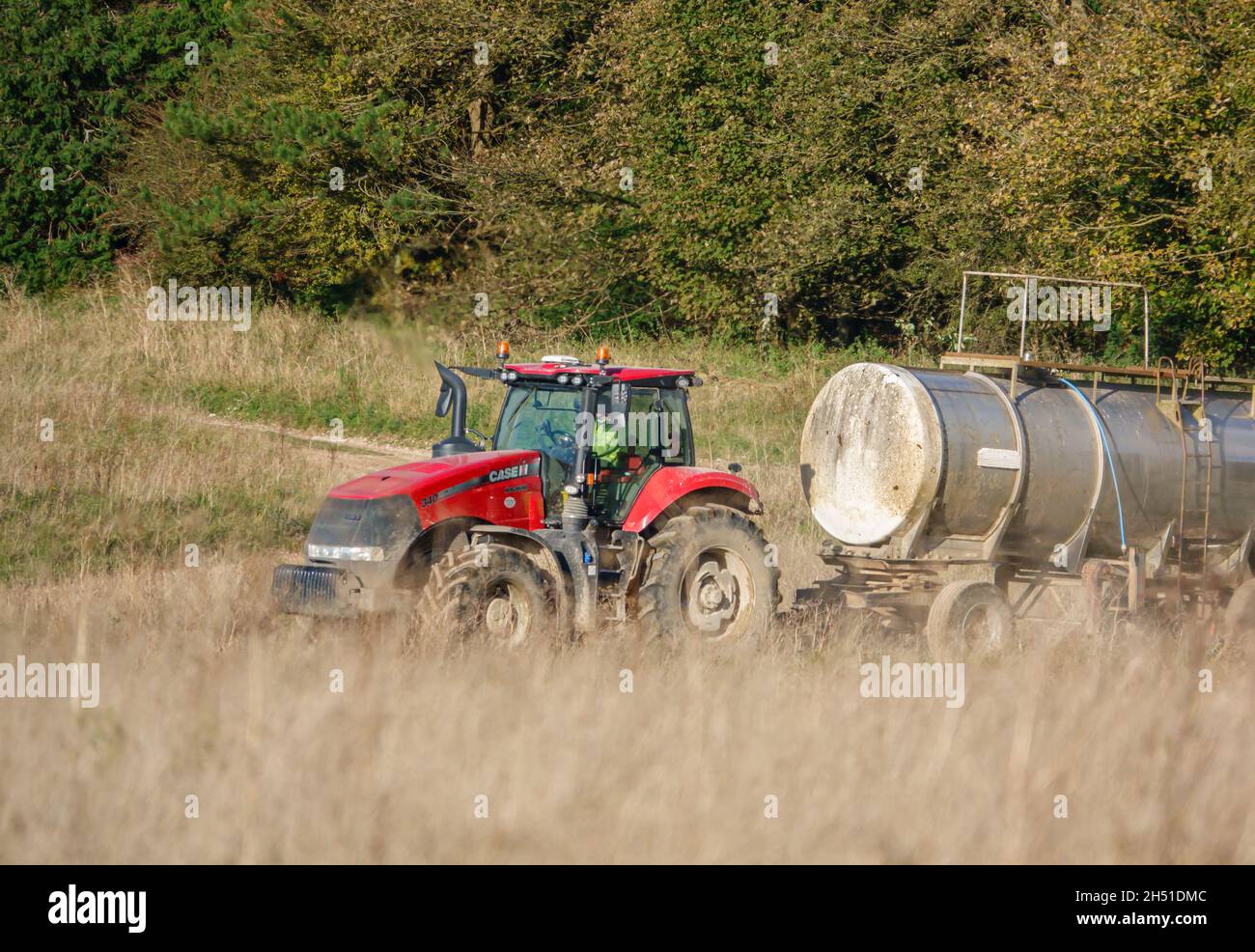 Ein großer Red Case 340 Magnum Traktor schleckt einen 30 Tonnen schweren Wasseranhänger über Ackerland Stockfoto
