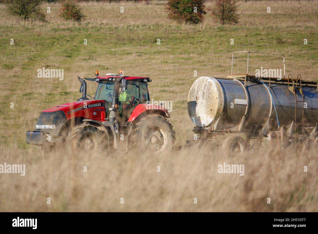 Ein großer Red Case 340 Magnum Traktor schleckt einen 30 Tonnen schweren Wasseranhänger über Ackerland Stockfoto