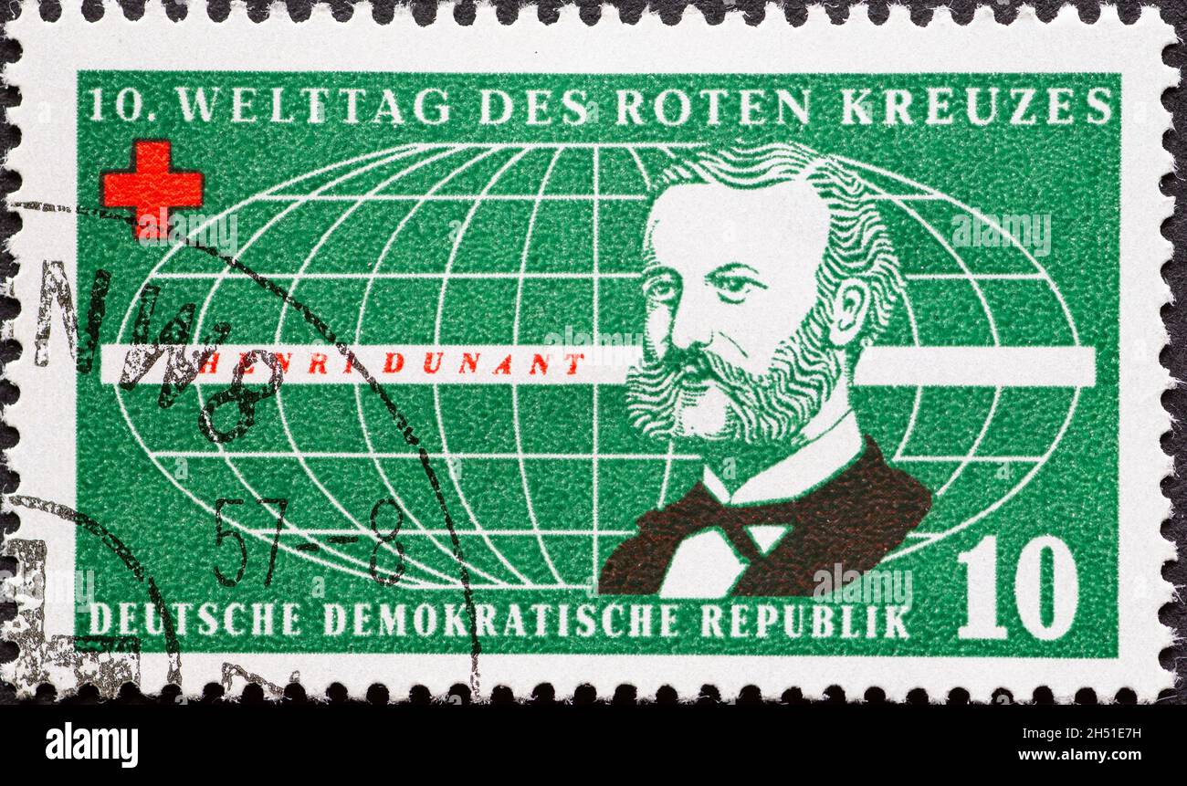 DEUTSCHLAND, DDR - UM 1957 : eine Briefmarke aus Deutschland, DDR mit einem Porträt von Henry Dunant, Mitbegründer des Roten Kreuzes, vor einem stilisierten Stockfoto