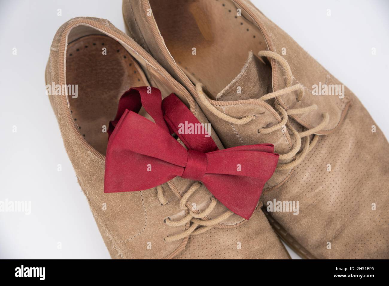 Accessoires für den Bräutigam. Schuhe auf weißem Hintergrund mit roten Wildleder-Schuhen mit Schmetterlingsdesign. Blick von oben, Bokeh. Stockfoto
