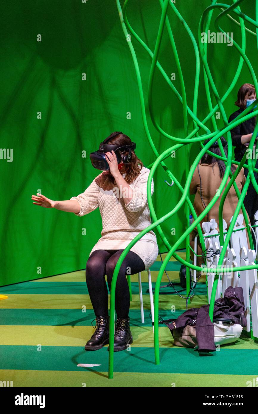 Frau mit VR-Headset spielt „Curious Alice“ VR-Erlebnis von HTC Vive Arts, „Alice: Curiouser and Curiouser“ 2021 Ausstellung auf der V&A, London, Großbritannien Stockfoto