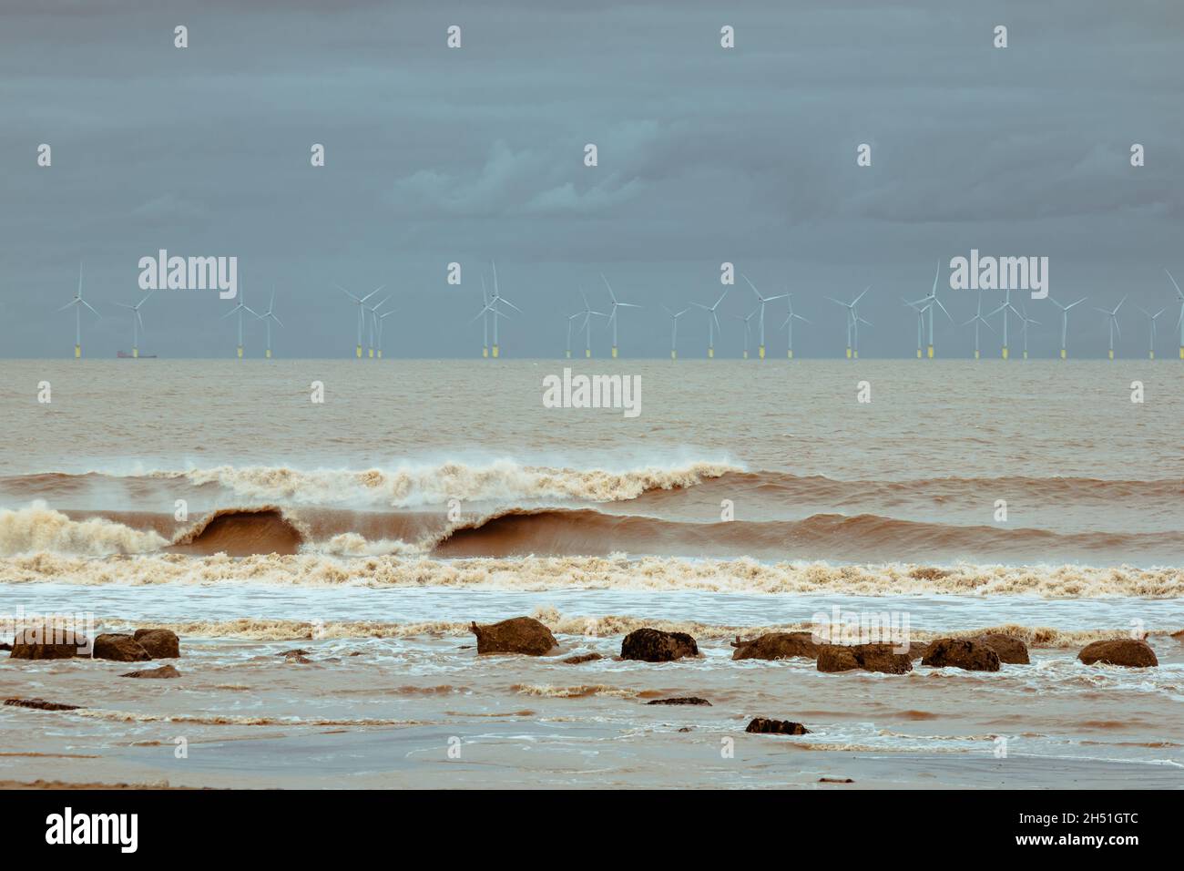 Küstenlandschaft am Spurn Point, mit turbulenten Meereswellen und dem Windpark an einem stürmischen Tag Stockfoto