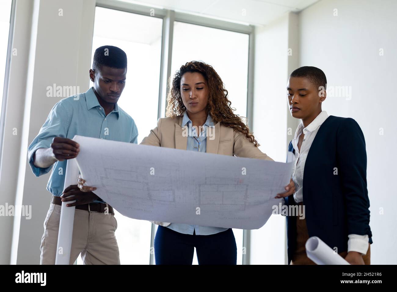 Biracial Architekt diskutiert mit Kollegen über Blaupause im Kreativbüro Stockfoto