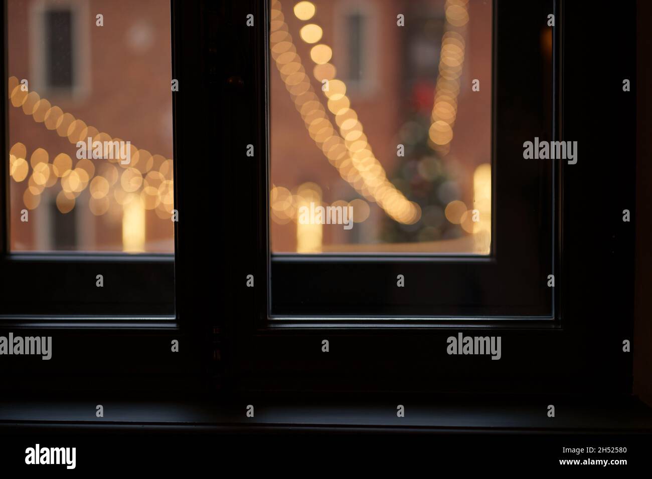 Blick vom Fenster aus auf den Stadtplatz mit geschmücktem weihnachtsbaum, Girlande-Lichter für das neue Jahr Stockfoto