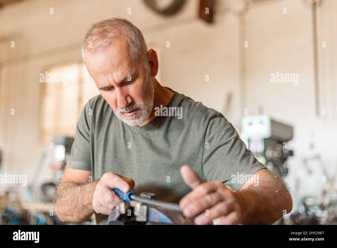 Männliche Person, die ein Metallwerkzeug einreicht. Zimmerei Stockfoto