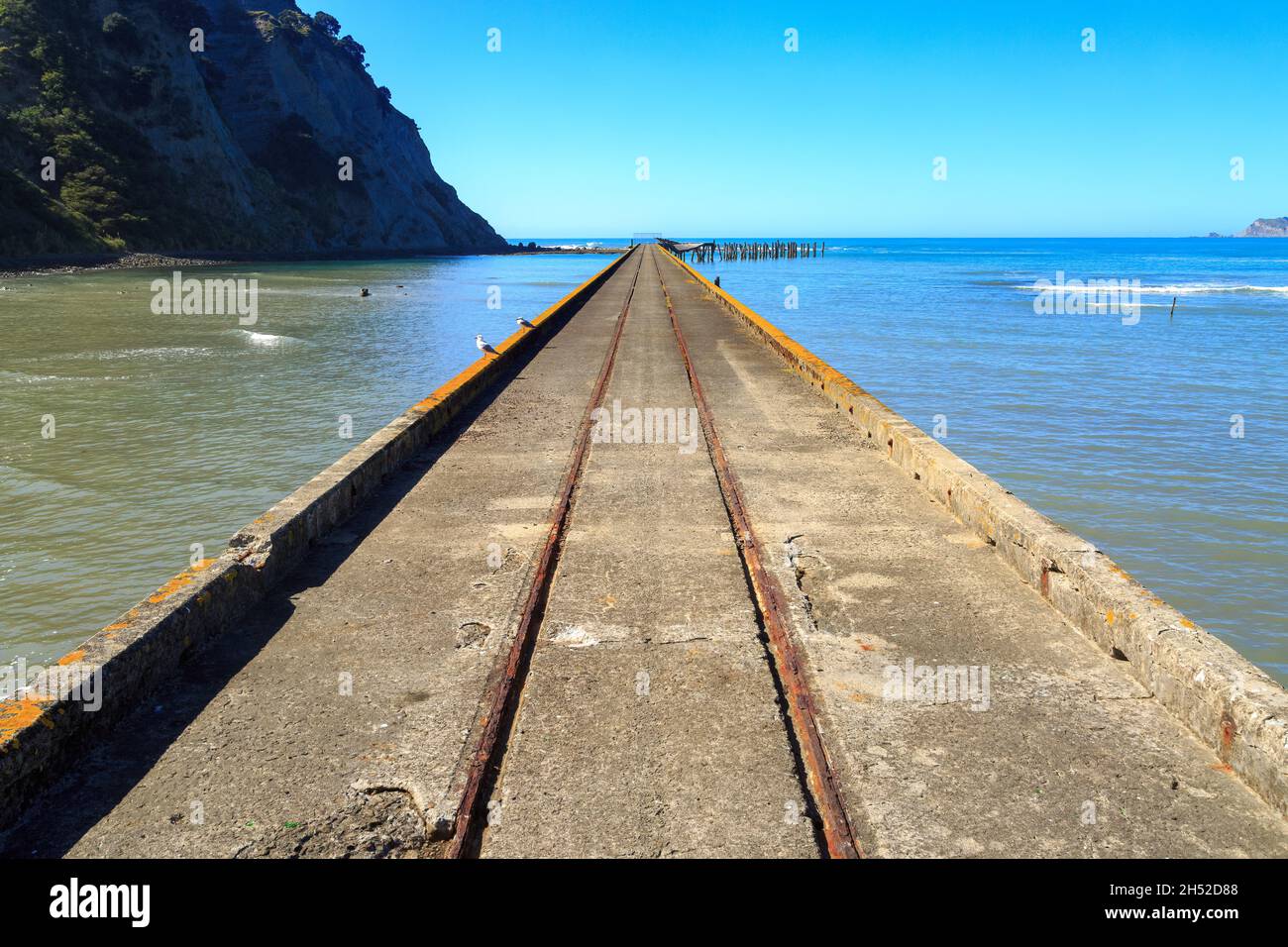 Der historische Betonwharf an der Tokomaru Bay, Neuseeland (erbaut 1940), der sich bis weit in den Ozean erstreckt Stockfoto