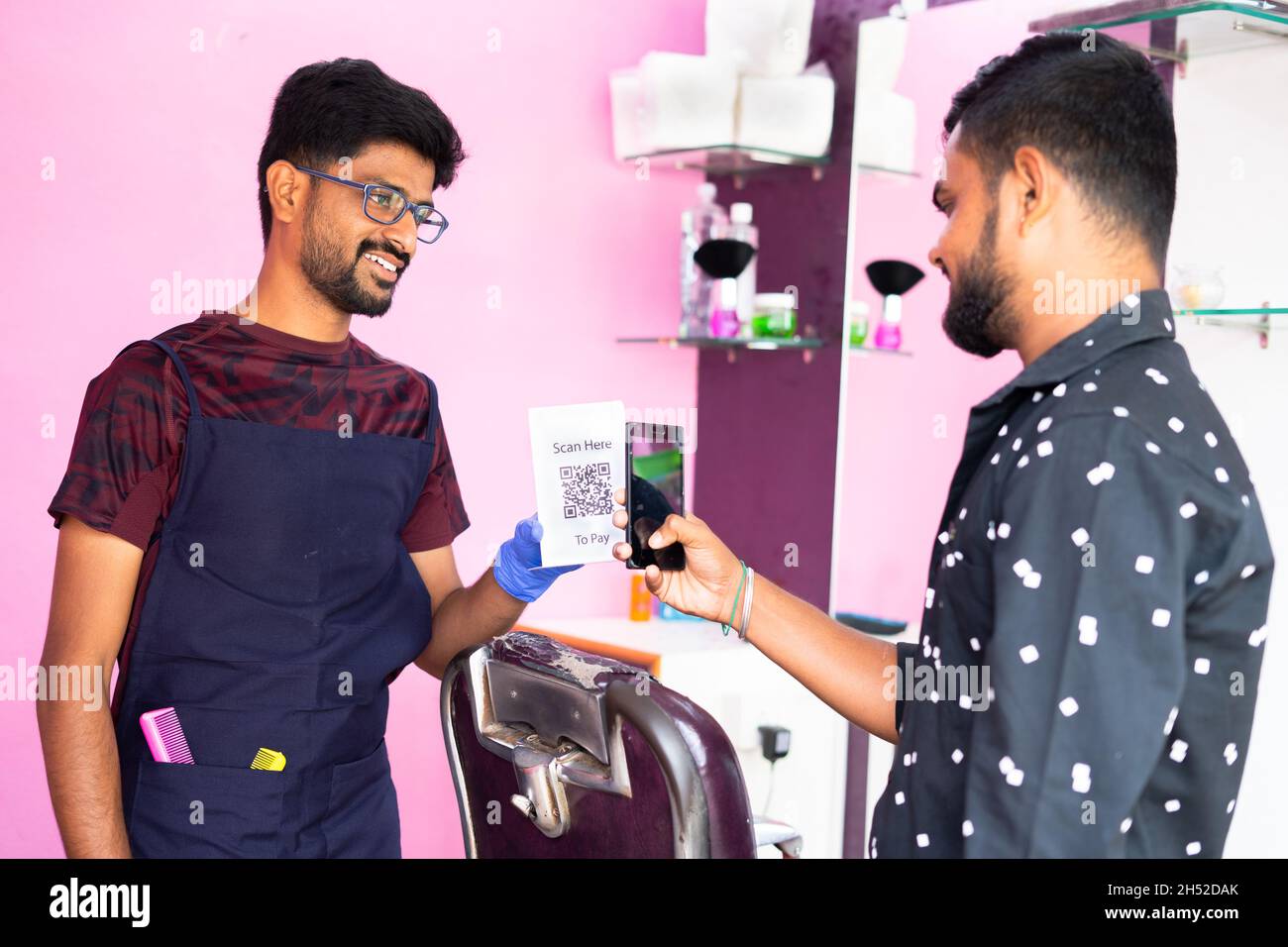 Kunde scannt QR-Code im Smartphone für die Zahlung an baber im Friseurladen - Konzept der digitalen Zahlung, Cashless-Technologie, empfehlen E Stockfoto
