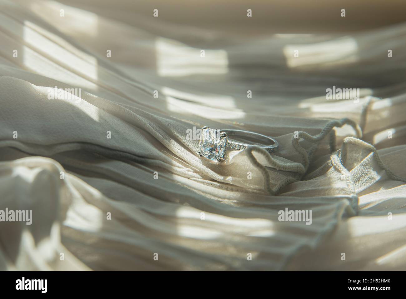 Nahaufnahme des eleganten Diamantrings auf grauem Schal-Hintergrund. Luxus Diamanten Schmuck Accessoire. „I Love You Darling“-Konzept. Stockfoto