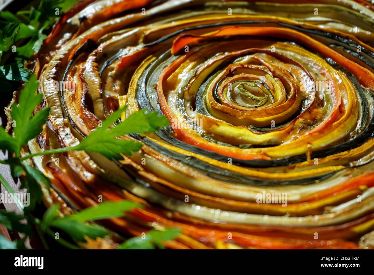 Gemüsekuchen mexikanische Sonne. Runde, offene Torte aus Zucchini, Auberginen und Karotten. Nahaufnahme von oben. Gesunde pflanzliche Lebensmittel. Vegetarismus. Spiralherb mit Auberginen. Stockfoto