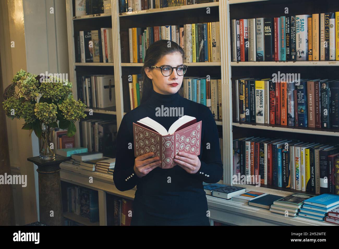 GREAT BRITAN / London / Buchhandlungen / schöne Frau, die ein Buch in einer Buchhandlung liest. Stockfoto