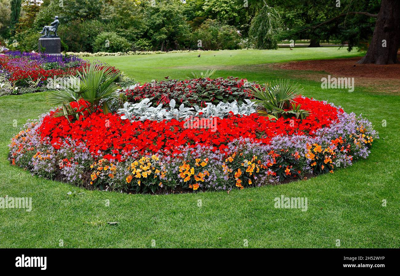Bunte Blumenbeet, Kreis, mehrere Farben, grünes Gras, Bäume, Statue, Botanischer Garten; Südinsel, Christchurch; Neuseeland Stockfoto