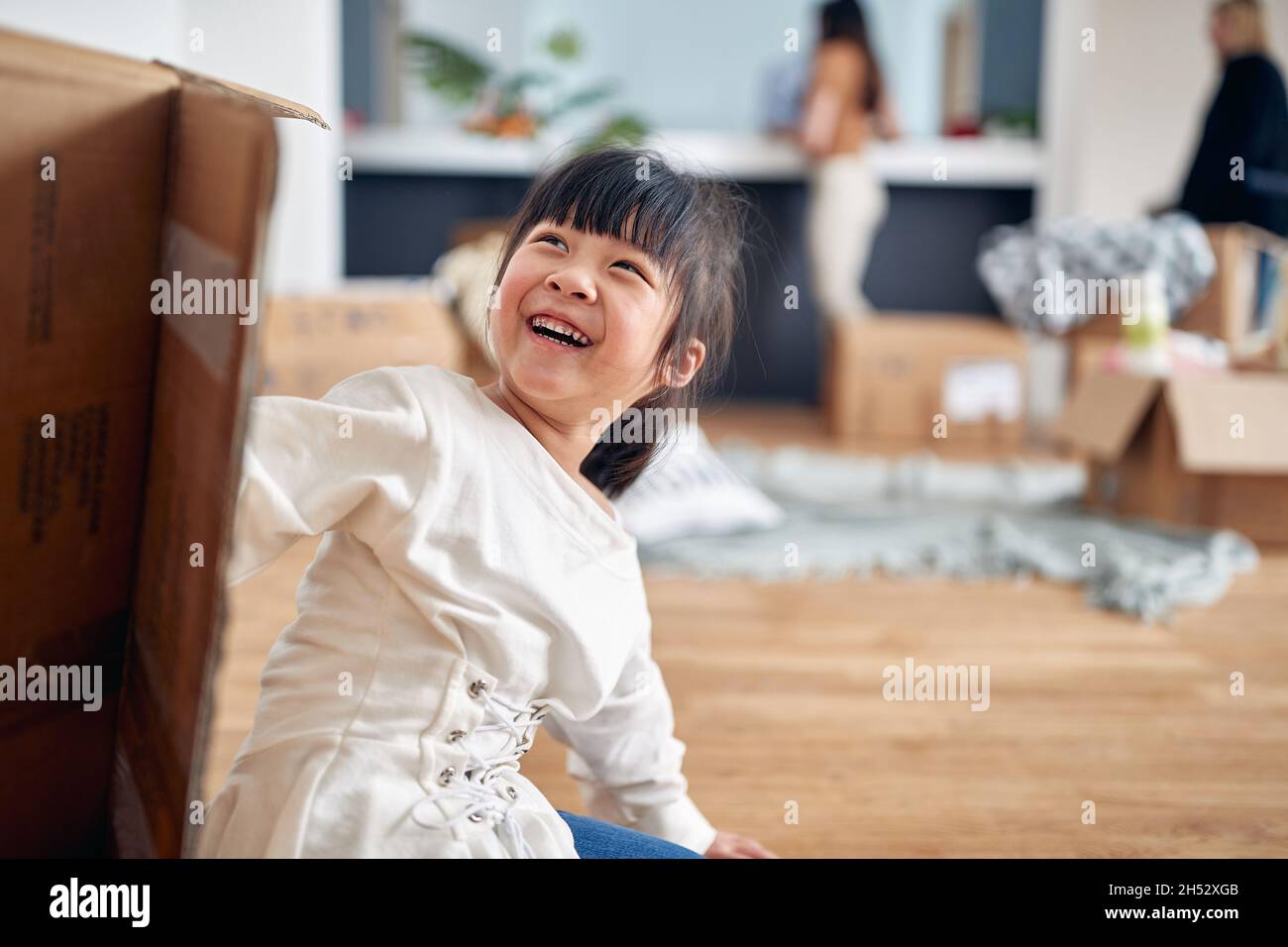 Ein kleines Mädchen spielt auf dem Boden in einer fröhlichen Atmosphäre in einem neuen Zuhause, in dem ihre Familie gerade eingezogen ist. Zuhause, Familie, Umzug Stockfoto