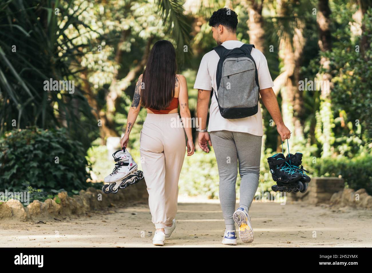 Zwei junge Leute, die in einem Park mit Inline-Skates spazieren gehen Stockfoto