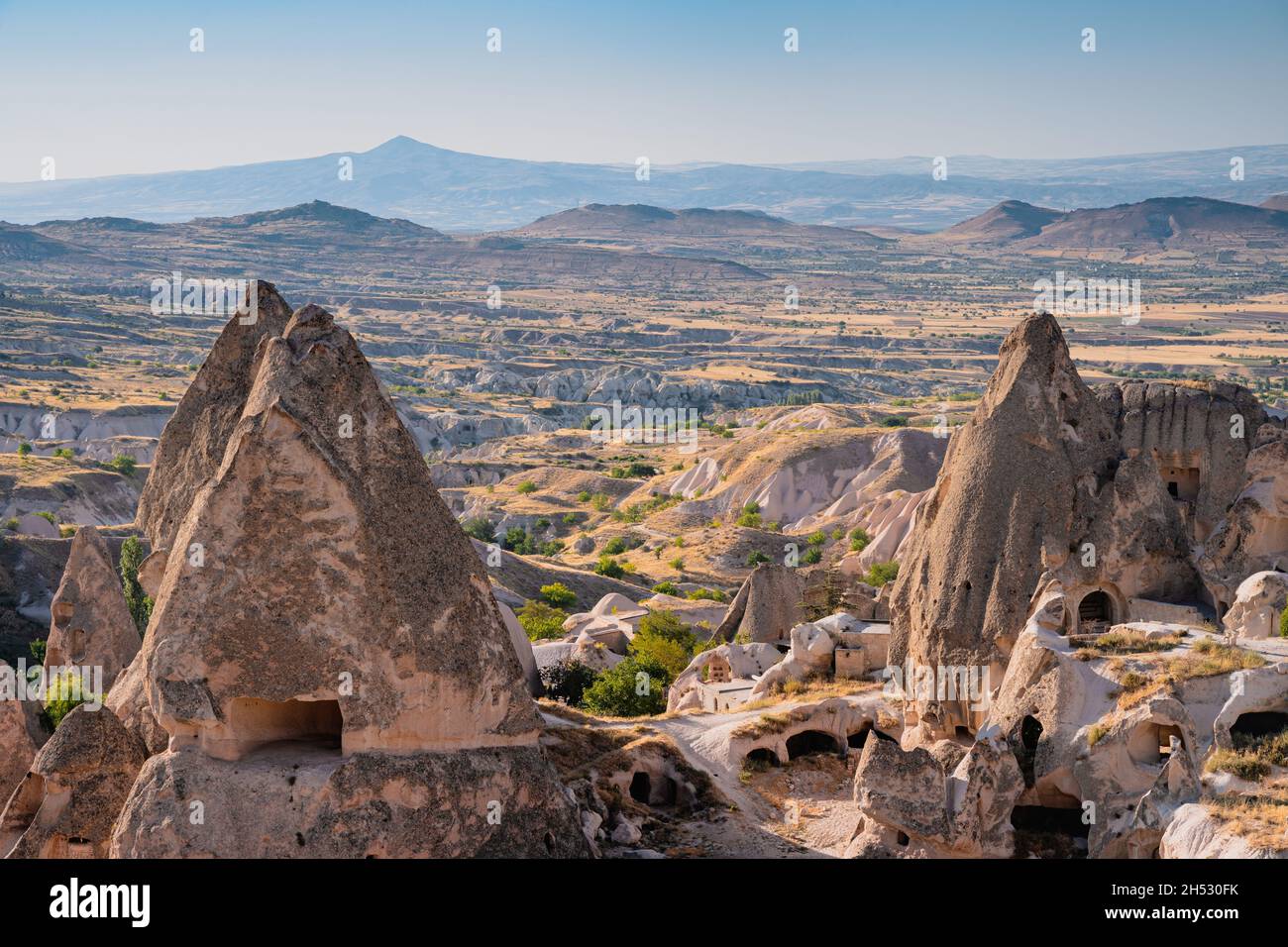 Wunderschöne Sonnenuntergangslandschaft im Tal von Cappadocia mit alten Höhlenhäusern im Vordergrund Stockfoto