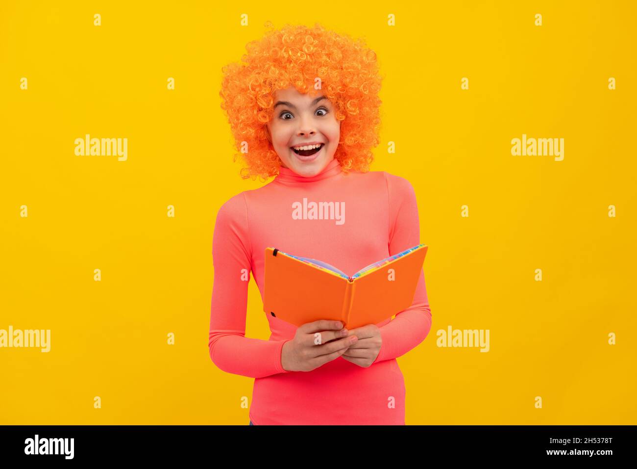 Glückliches Mädchen Kind mit orangen Haaren in rosa Poloneck Lächeln halten Schulbuch, Bildung Stockfoto