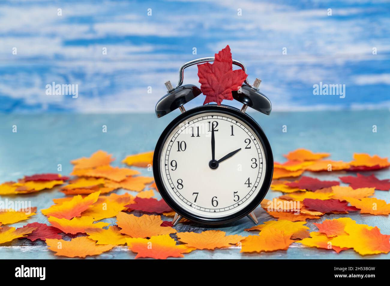 Wecker mit Herbstlaub - Zeitkonzept zur Sommerzeit Stockfoto