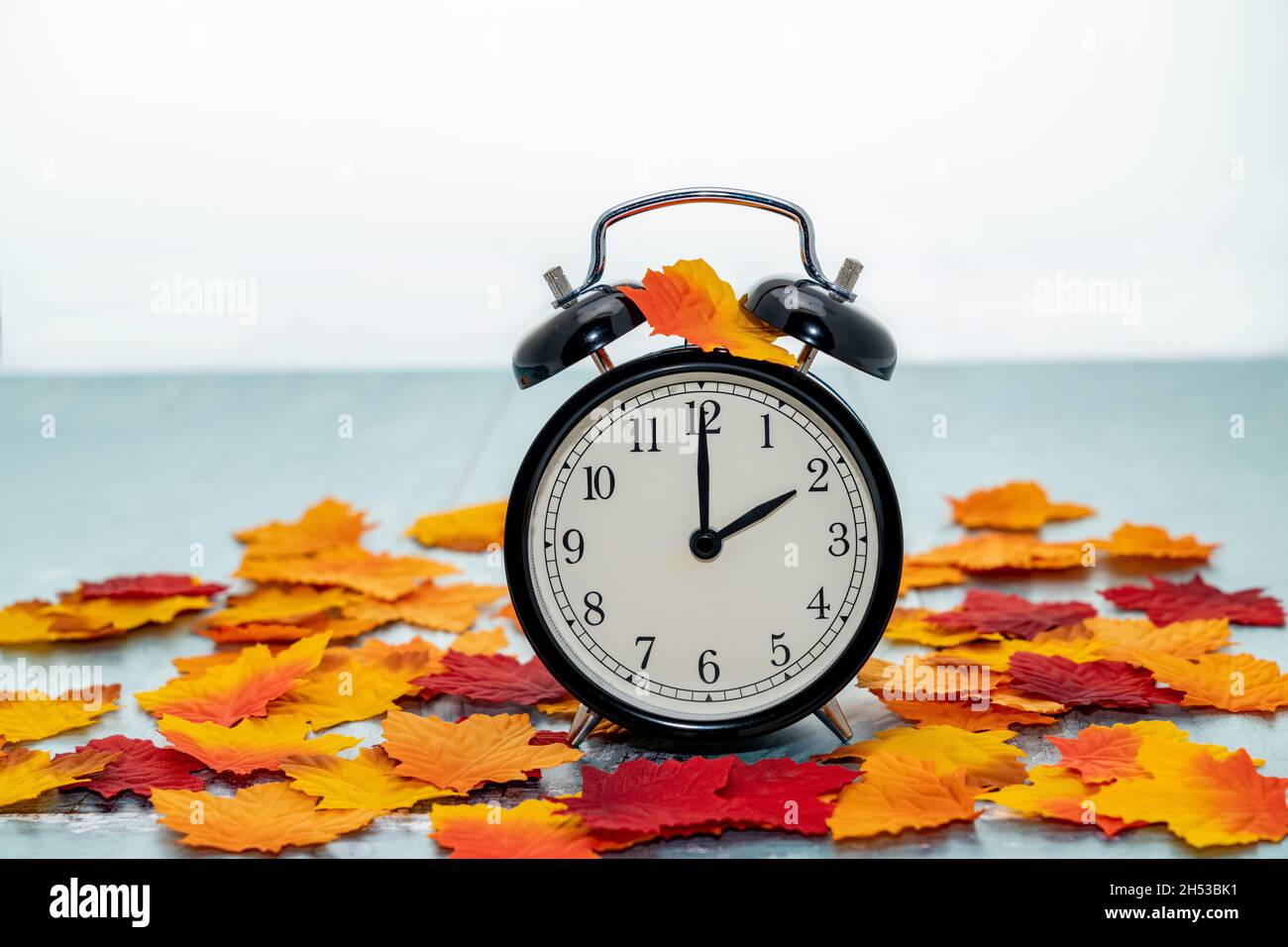 Wecker mit Herbstlaub - Zeitkonzept zur Sommerzeit Stockfoto
