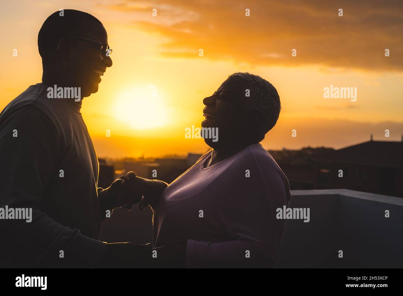 Glückliches lateinisches Seniorenpaar, das romantische Momente auf dem Dach tanzt Während der Sonnenuntergangszeit Stockfoto