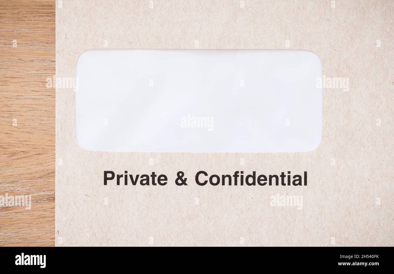 Fensterumschlag auf einem Schreibtisch, Großbritannien, als privat und vertraulich gekennzeichnet. Leerer Umschlag zur Verwendung als Vorlage oder Design. Stockfoto