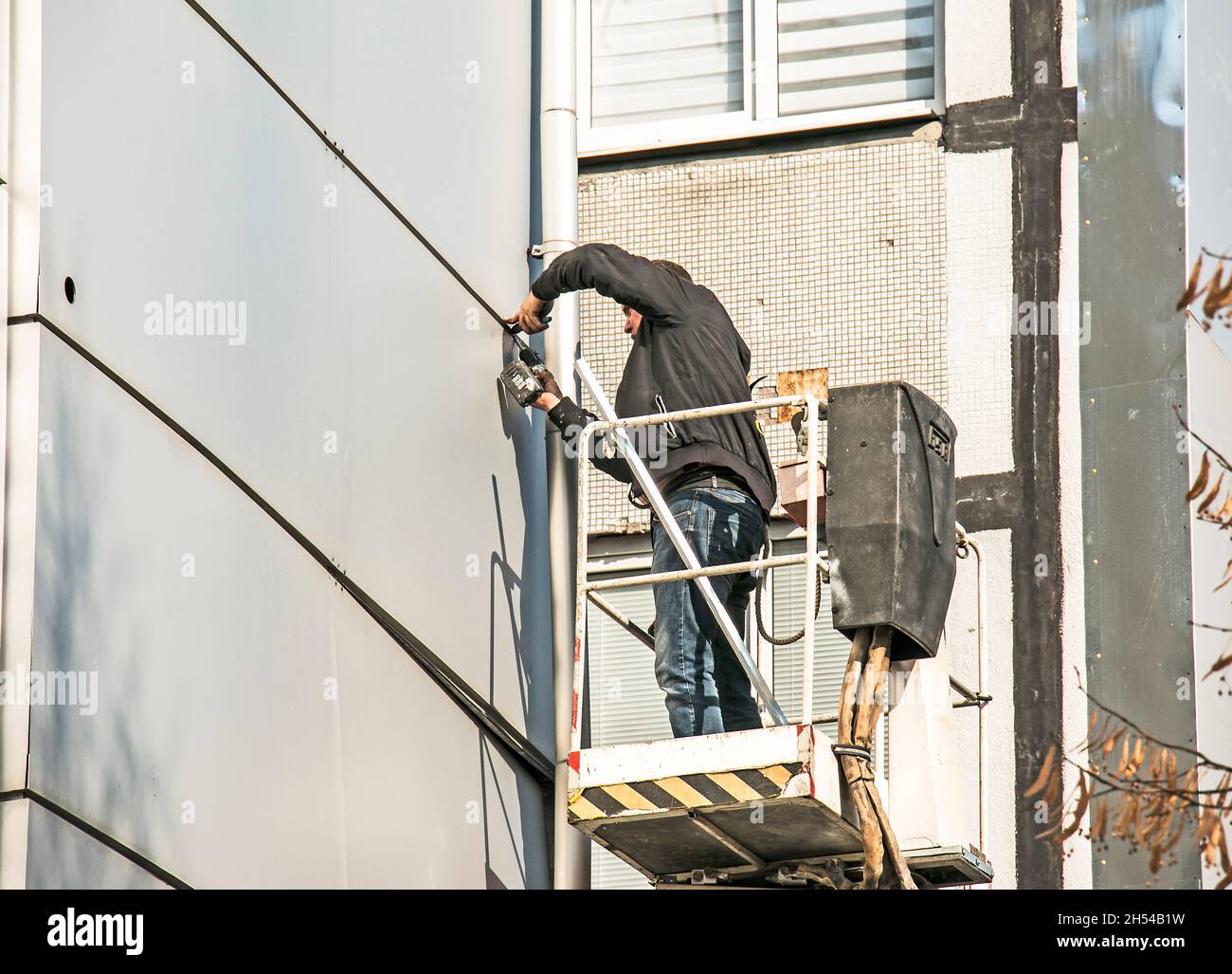 Dnepropetrovsk, Ukraine - 10.22. 2021: Ein Bauherr führt Hochhaus-Fassadenarbeiten an einem Hubkorb durch. Stockfoto