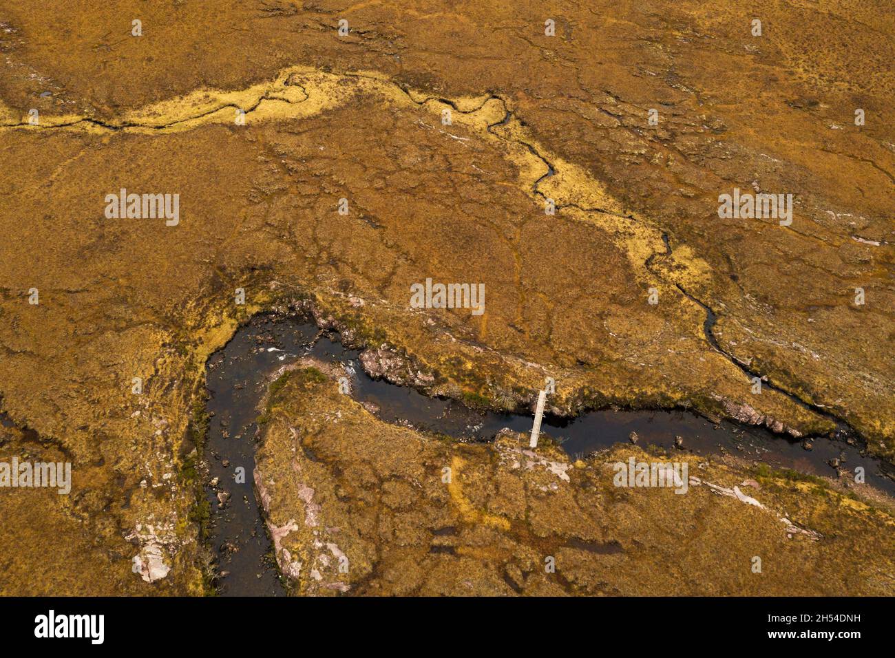 Eine Fußgängerbrücke über einen abgelegenen kleinen Fluss in Assynt, Nordschottland, die von Wanderern genutzt wird. Stockfoto