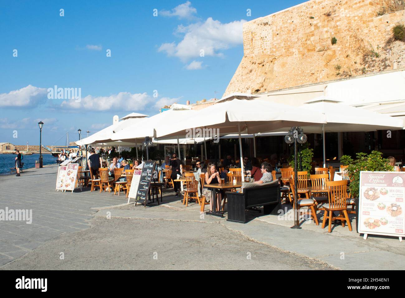 Chania, Kreta - Griechenland - Oktober 20 2021 : charmante gepflasterte Taverne am historischen venezianischen Hafen Urlauber genießen die Sommersonne Landschaft Stockfoto