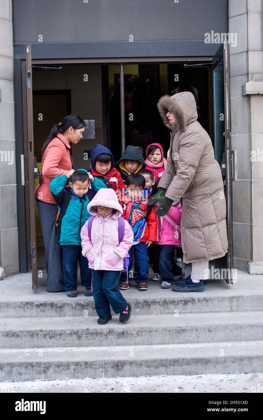 St. Paul, Minnesota. Charterschule für die Hmong. Hmong-Schüler verlassen an einem kalten Tag die Schule, um in den Schulbus zu steigen. Stockfoto