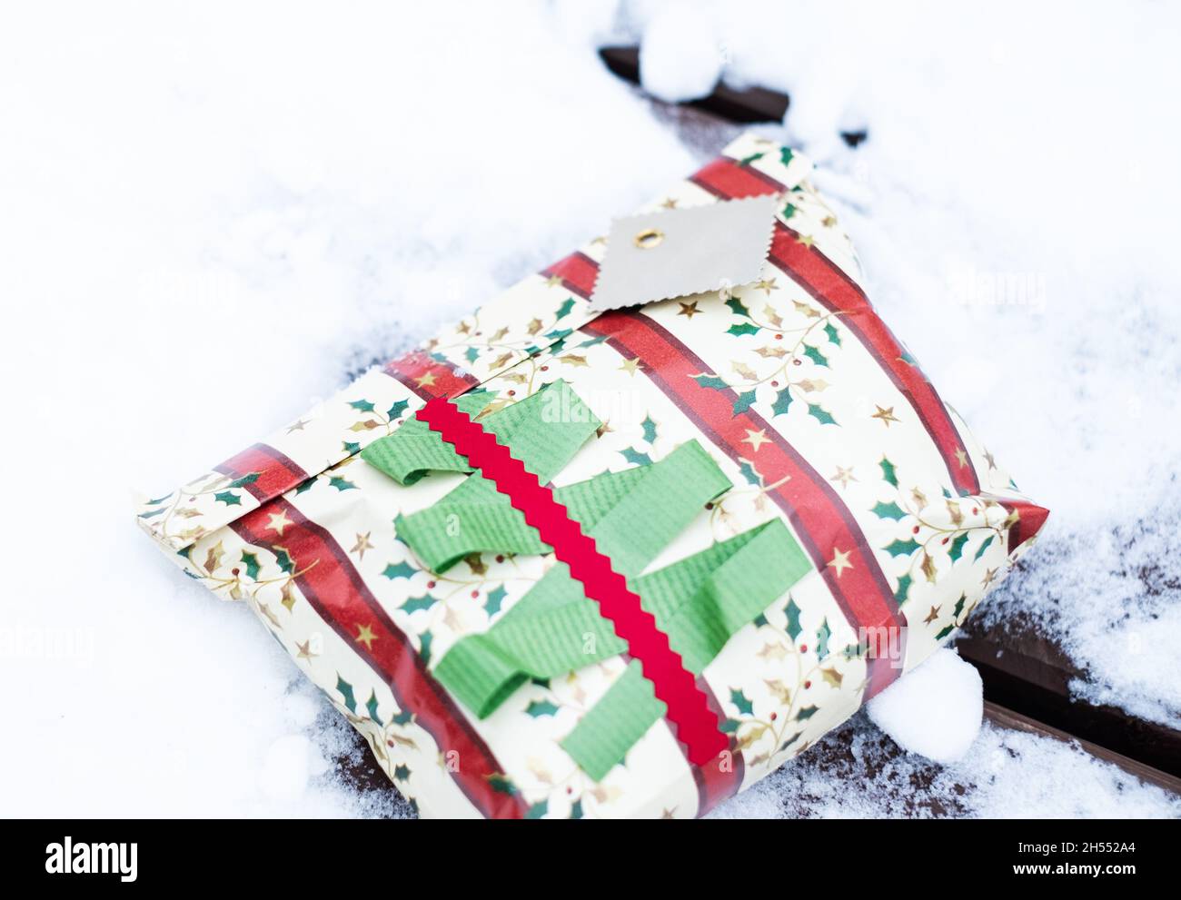 Weihnachtsgeschenk im Schnee. Wunderschön gewickelte Weihnachtsgeschenke liegen im Freien in natürlicher Umgebung im Winter, Ferienzeit. Stockfoto