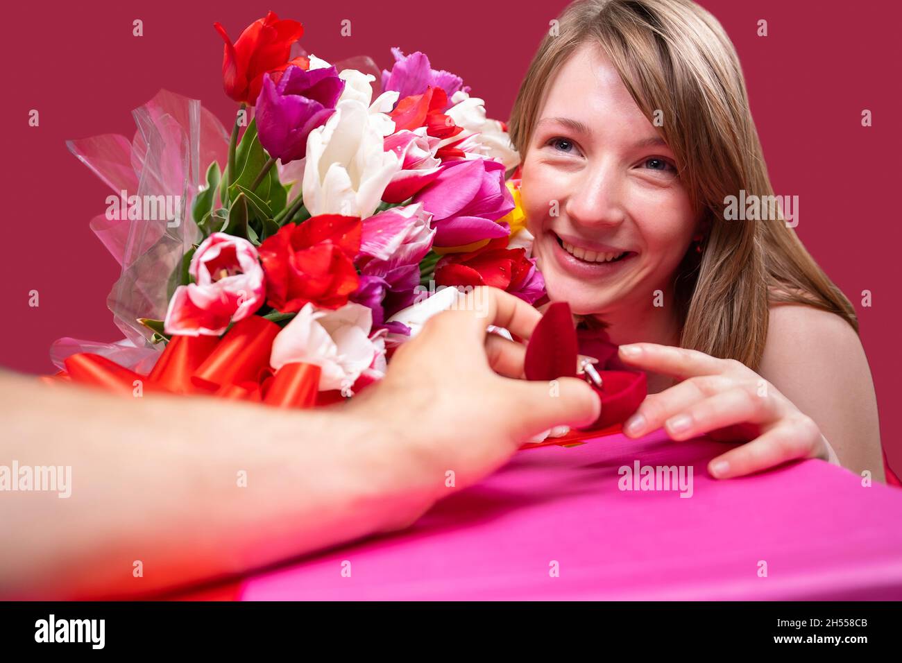 Nahaufnahme Foto einer schönen fröhlichen blonden Dame mit einem Tulpen farbigen Strauß und die Annahme der Heiratsantrag von ihrem Freund, er hält einen Stockfoto