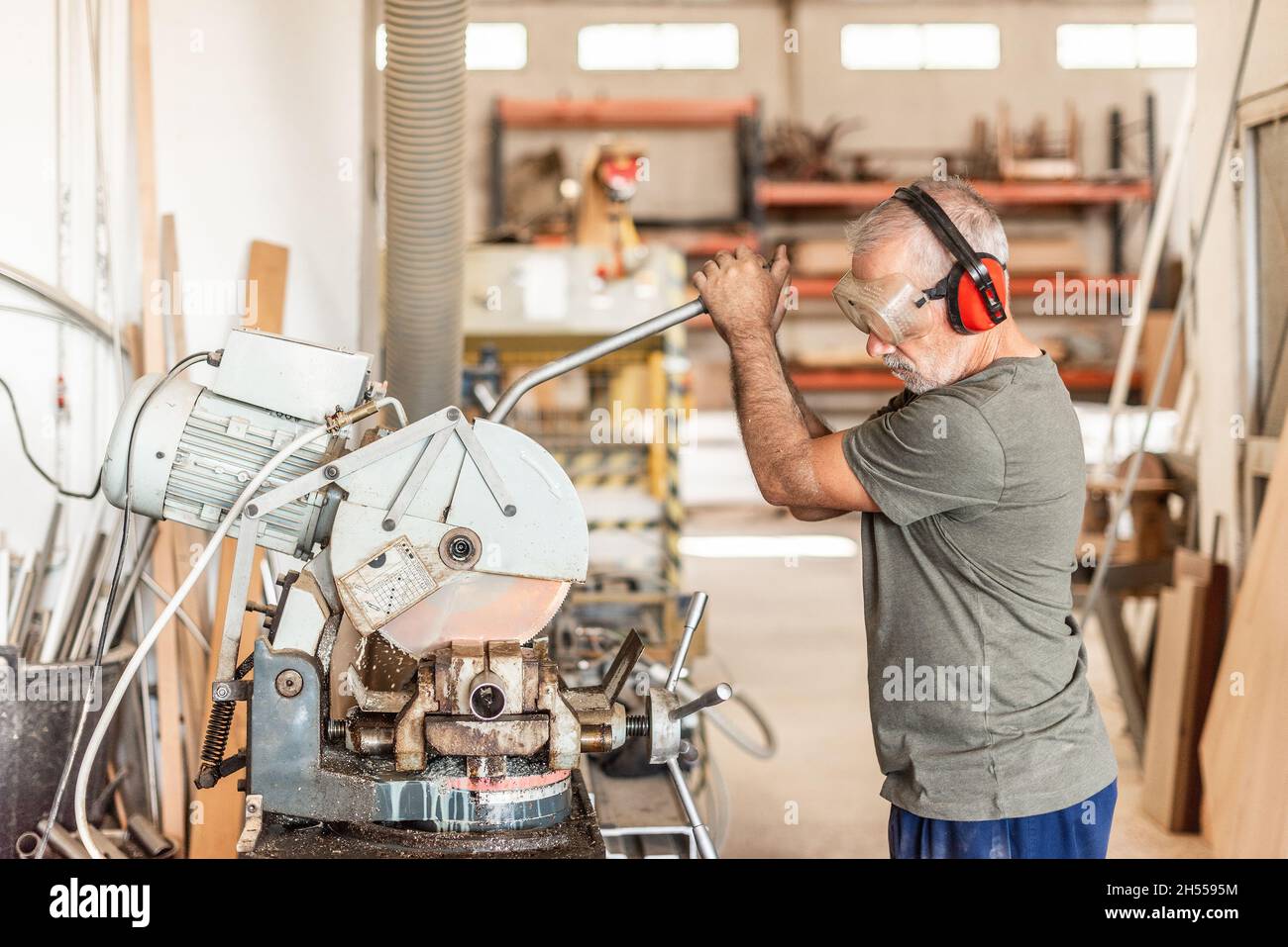 Arbeiter in Sicherheitseinrichtungen, die ein Edelstahlrohr schneiden Stockfoto