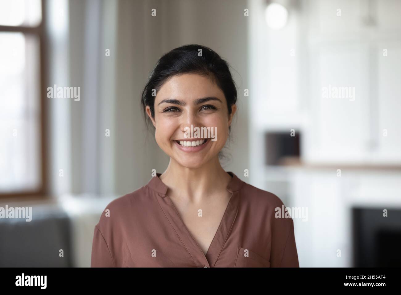 Indisches Weibchen mit breitem Lächeln, das in der Halle vor der Kamera posiert Stockfoto