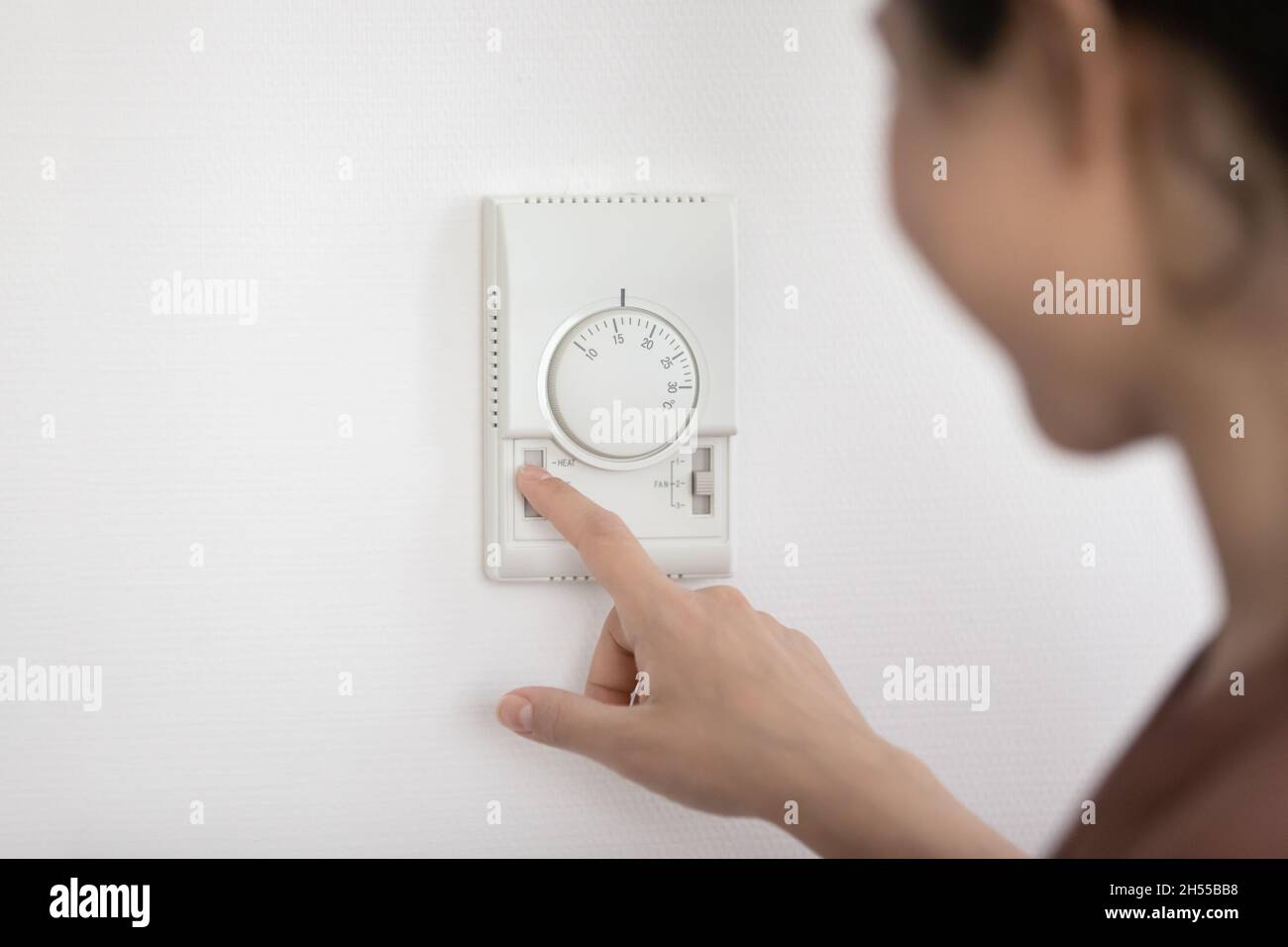 Frau, die die Temperatur im Inneren für Wirtschaftlichkeit und Komfort einlegt Stockfoto