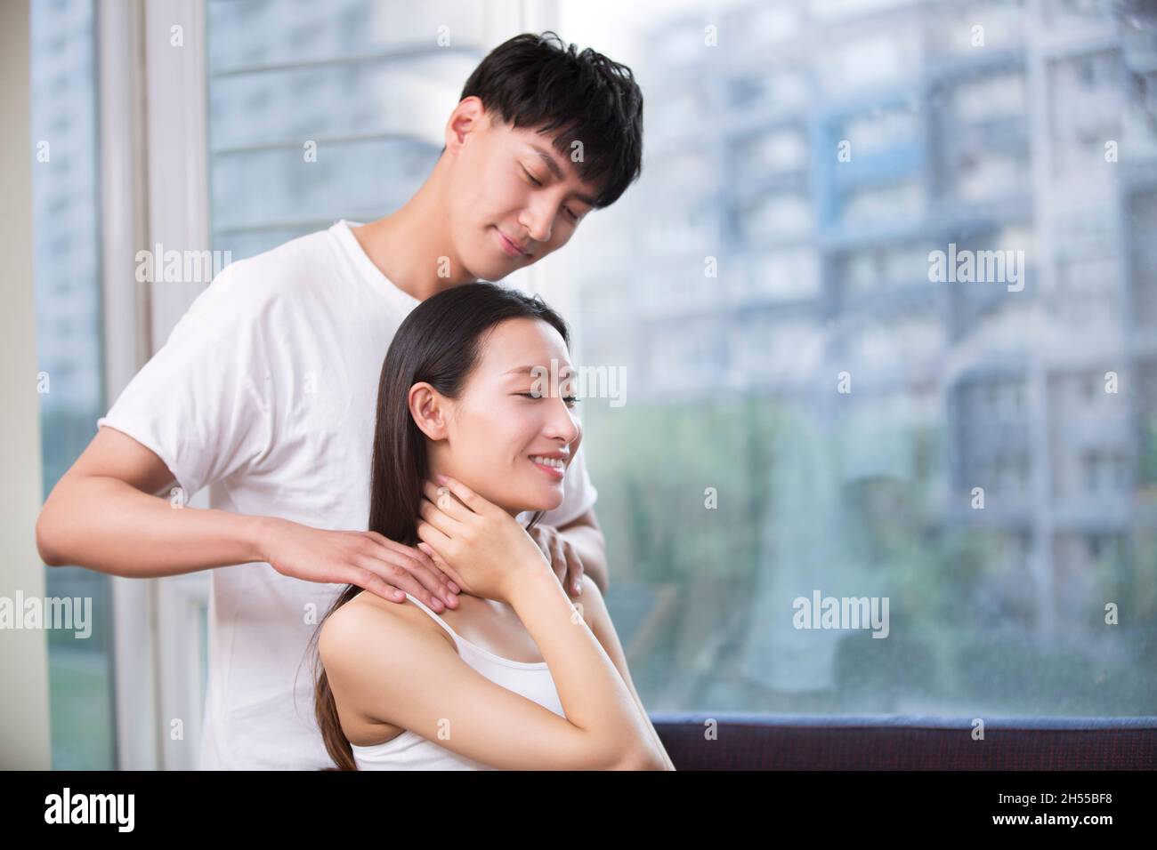 Junger Mann massiert seine Freundin Stockfoto