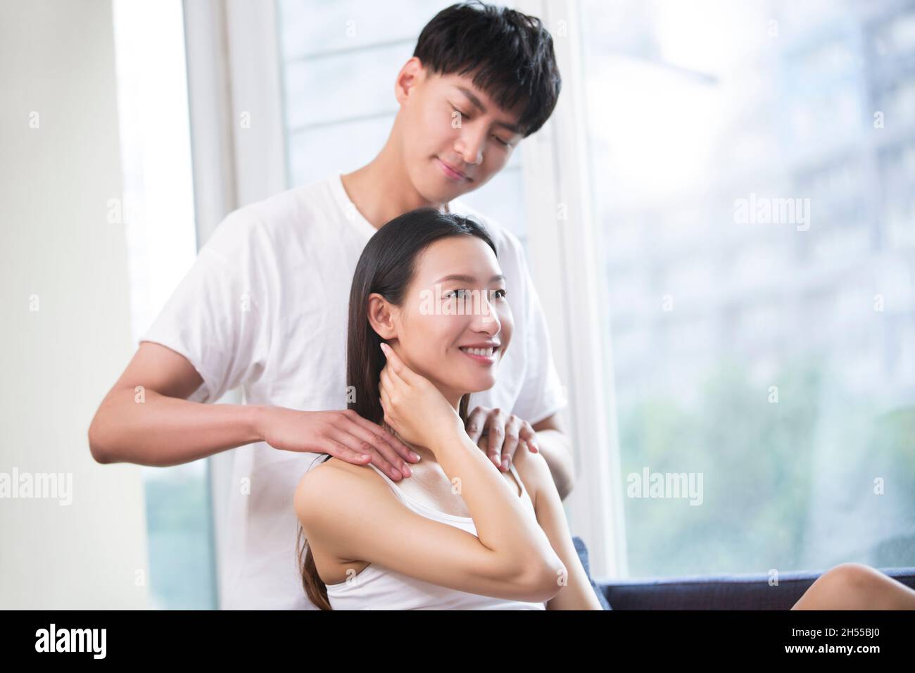 Junger Mann massiert seine Freundin Stockfoto