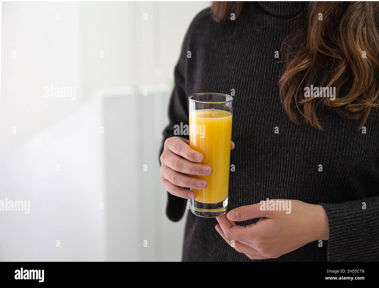 Ein Glas Orangensaft in weiblichen Händen, Nahaufnahme. Stockfoto