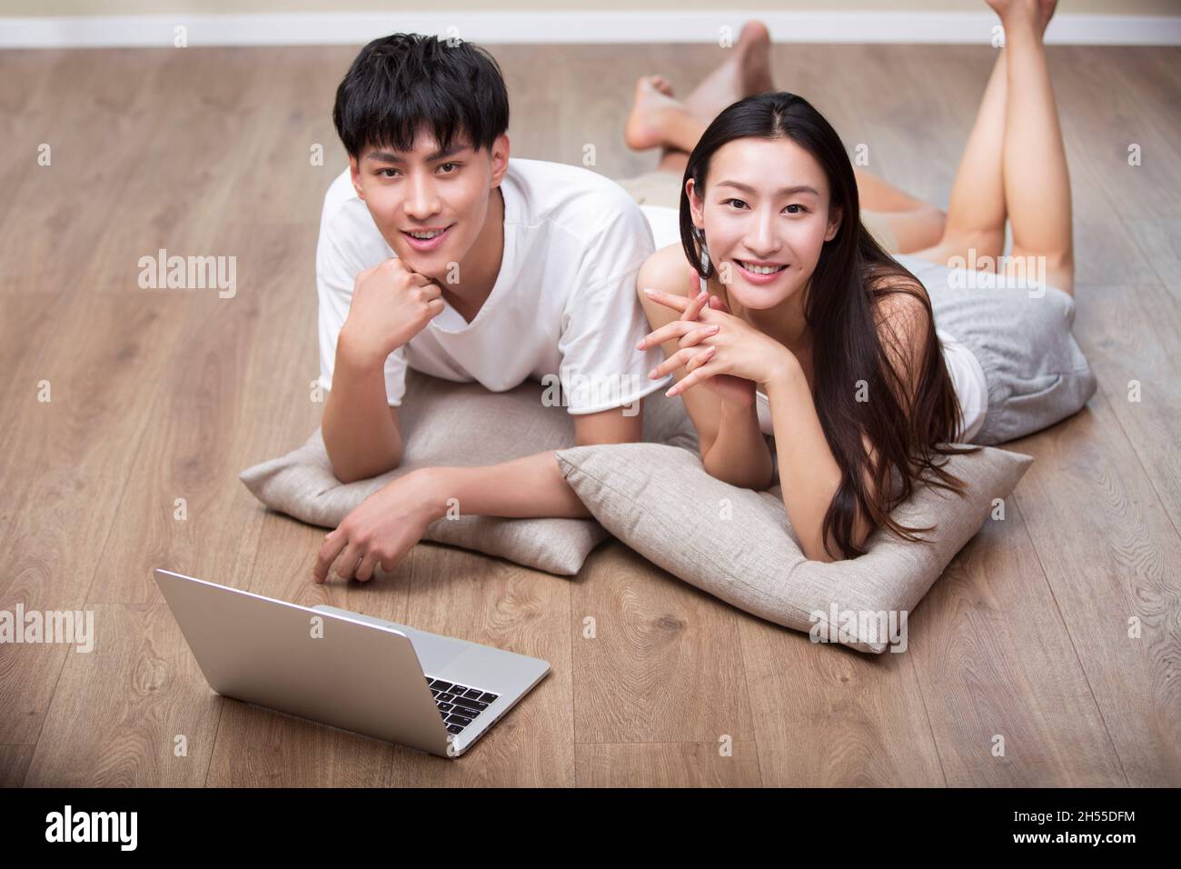 Junges Paar, das auf dem Boden liegt und ein digitales Tablet benutzt Stockfoto
