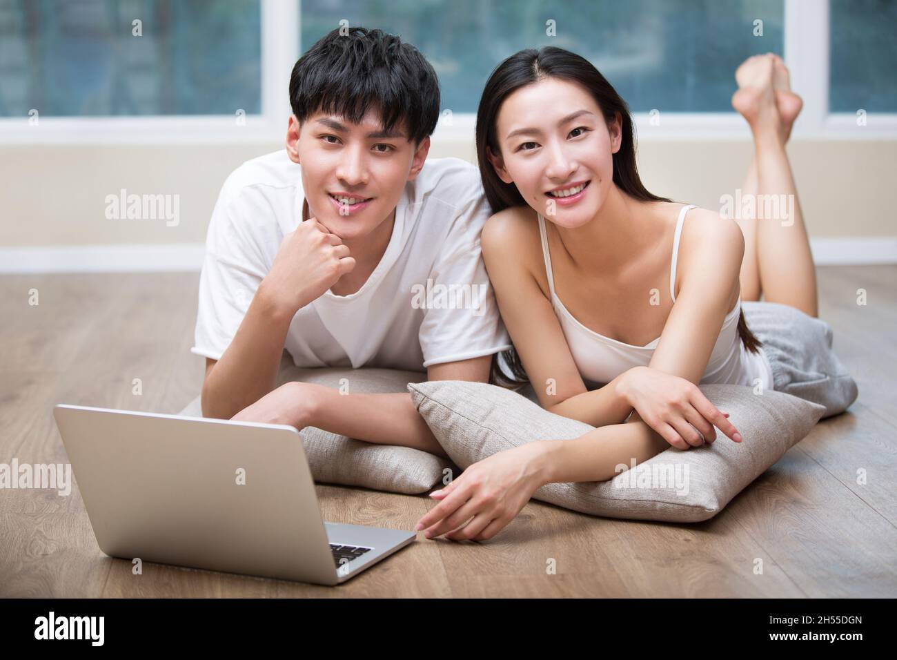 Junges Paar, das auf dem Boden liegt und ein digitales Tablet benutzt Stockfoto