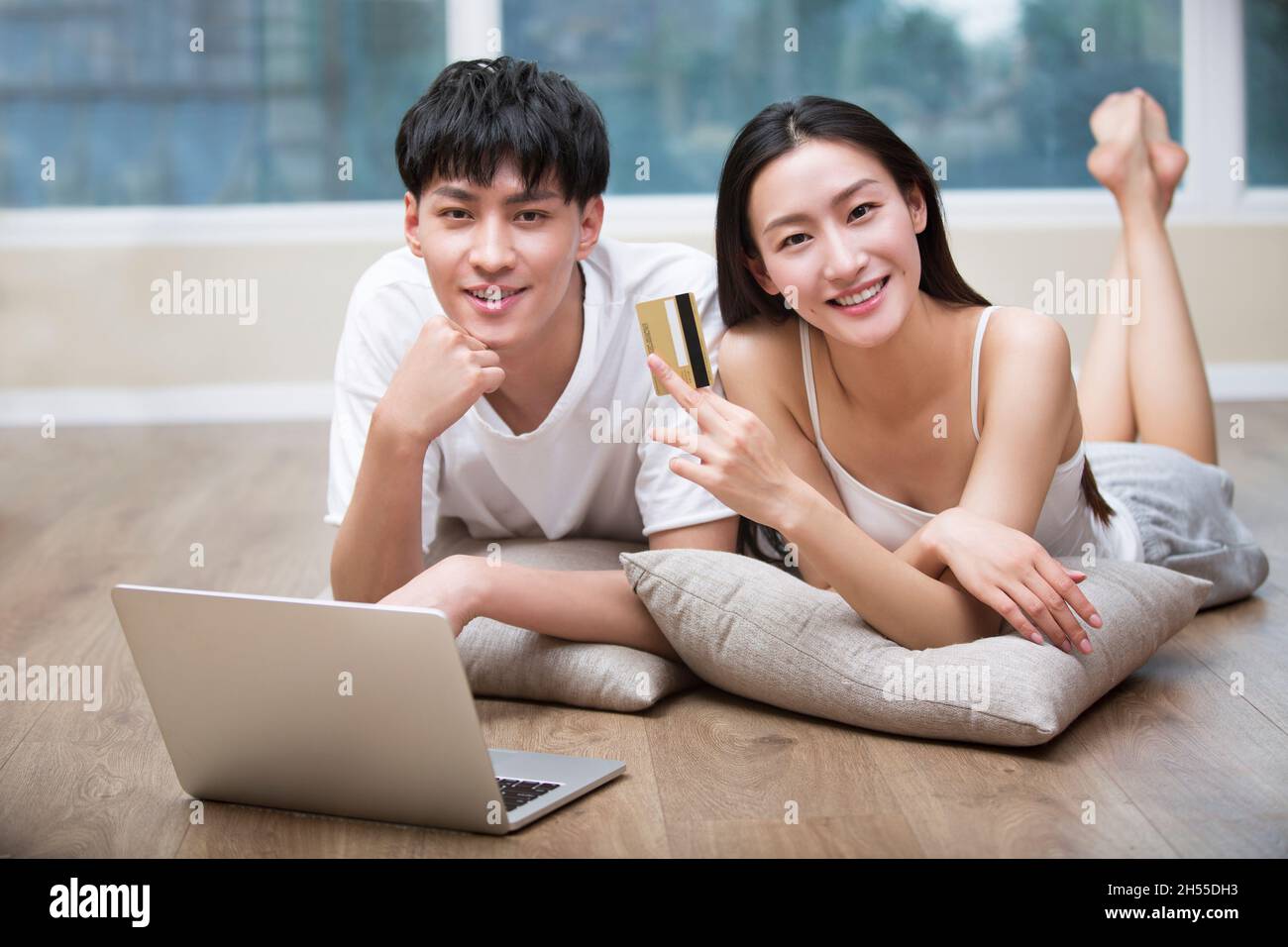 Junges Paar, das auf dem Boden liegt und mit einem digitalen Tablet online einkaufen geht Stockfoto