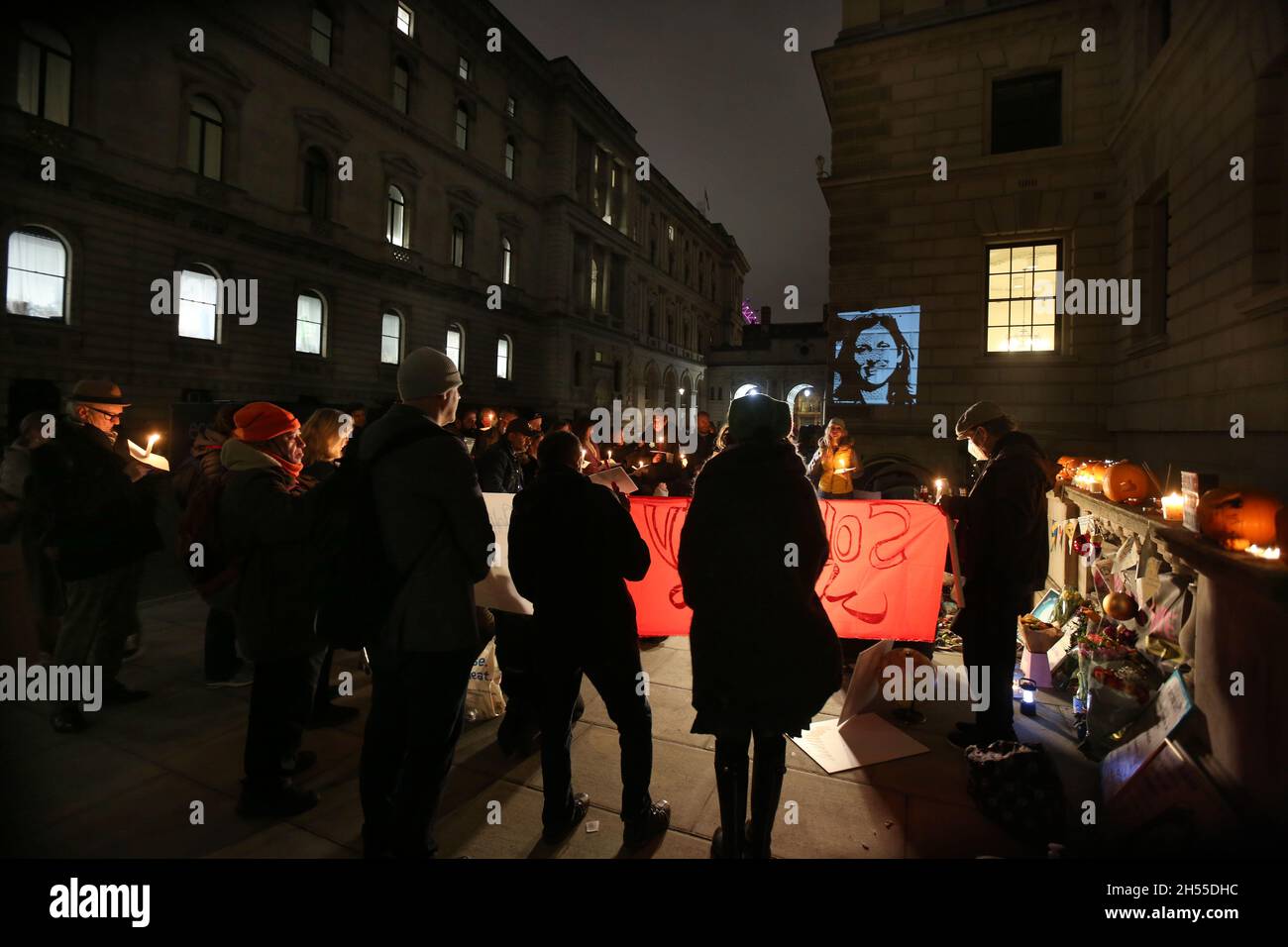 London, Großbritannien. November 2021. Ein Porträt von Nasanin wird auf die Wand projiziert, während Richard Ratcliffe und Tochter Gabriella eine Kerzenlicht-Mahnwache vor dem Auswärtigen Amt für ihre Frau und Mutter Nazanin Zaghari-Ratcliffe halten, die seit 2016 im Iran inhaftiert ist und wegen Verschwörung zum Sturz der iranischen Regierung inhaftiert ist. Kredit: SOPA Images Limited/Alamy Live Nachrichten Stockfoto