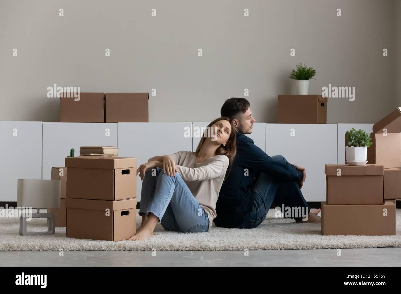 Müde unglückliches Paar, das mit Pappkartons auf dem Boden saß Stockfoto