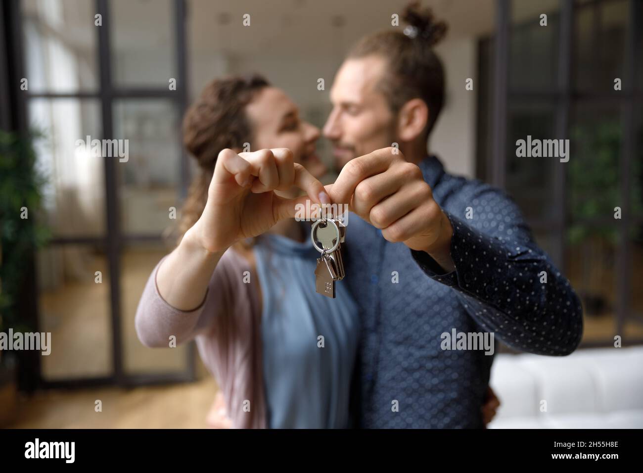 Liebevolles Familienpaar zeigt Schlüssel zur Kamera. Stockfoto