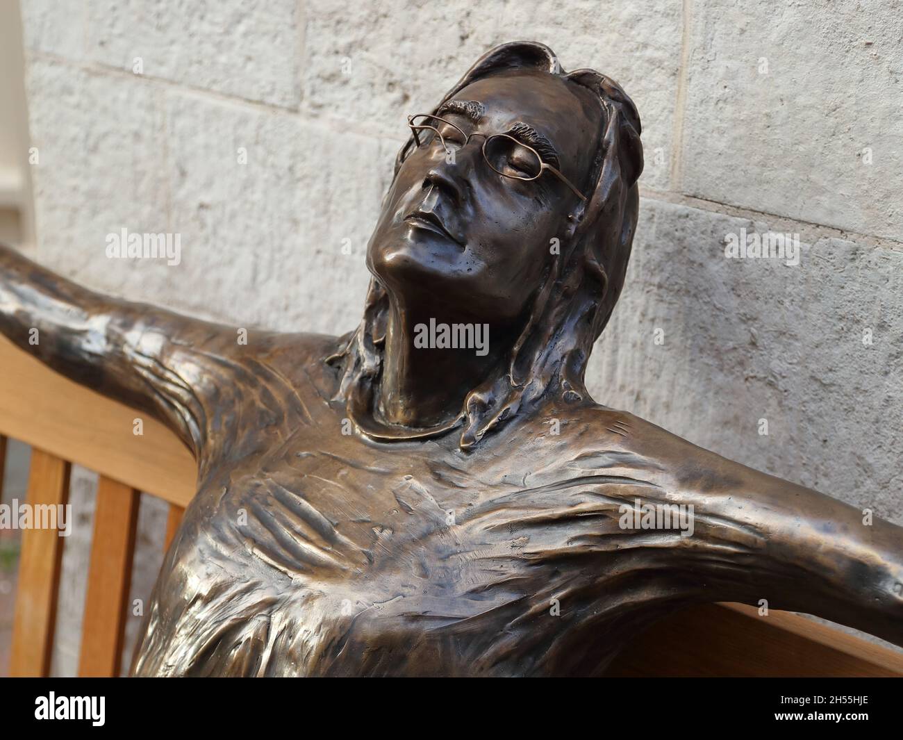 Lebensgroße Bronzeskulptur mit dem Baetle John Lennon, der auf einer Bank von Lawrence Holofcener in der Carnaby Street, London, Großbritannien, sitzt Stockfoto