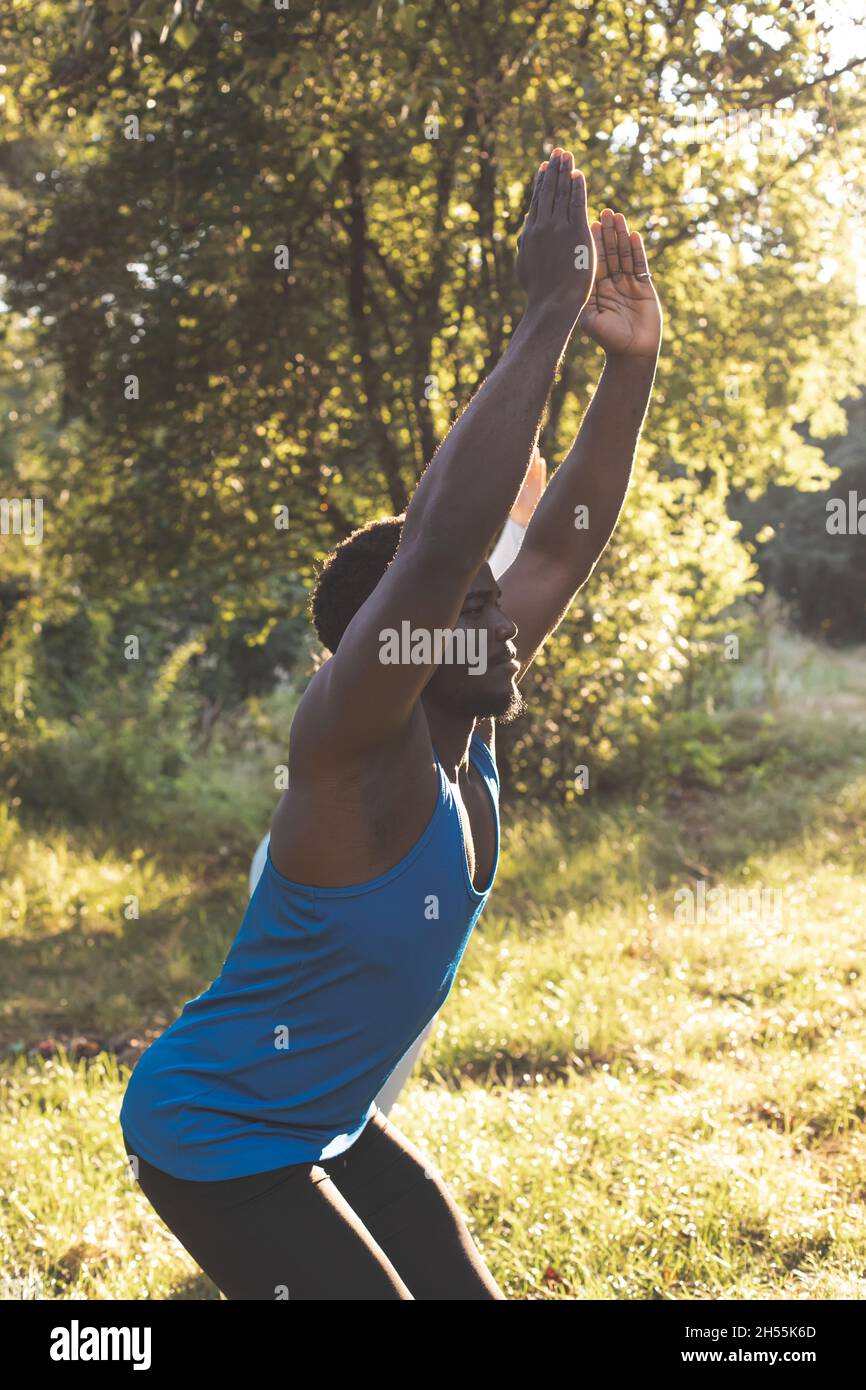 Der junge Mann in Sportbekleidung führt Yoga-Übungen durch. Der Mann streckt sich im Wald. Helles Licht hinter einer Person Stockfoto