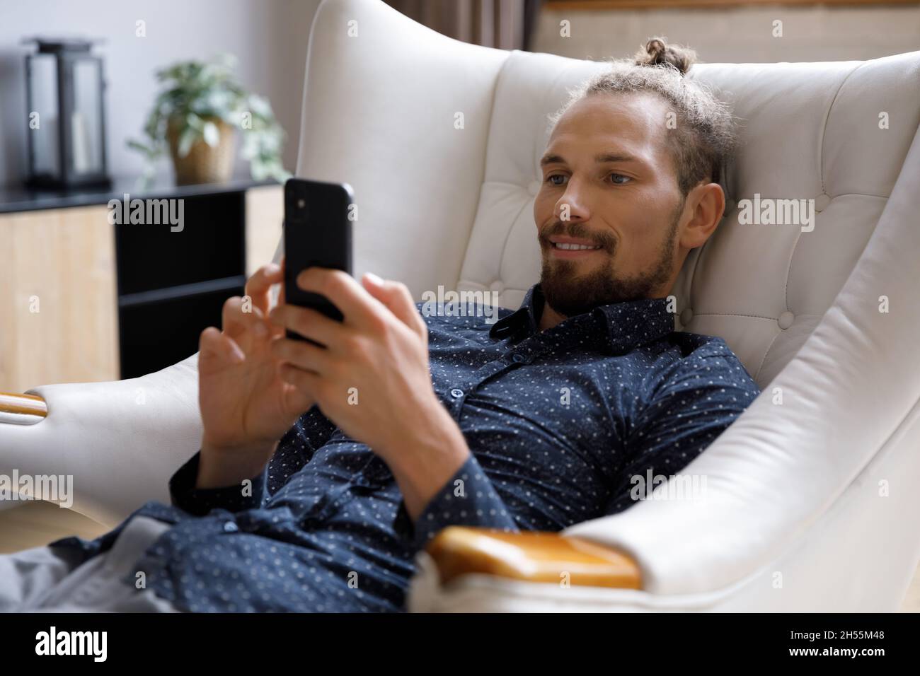 Glücklicher, unbeschwerter junger Mann, der mobile Software-Anwendungen verwendet. Stockfoto